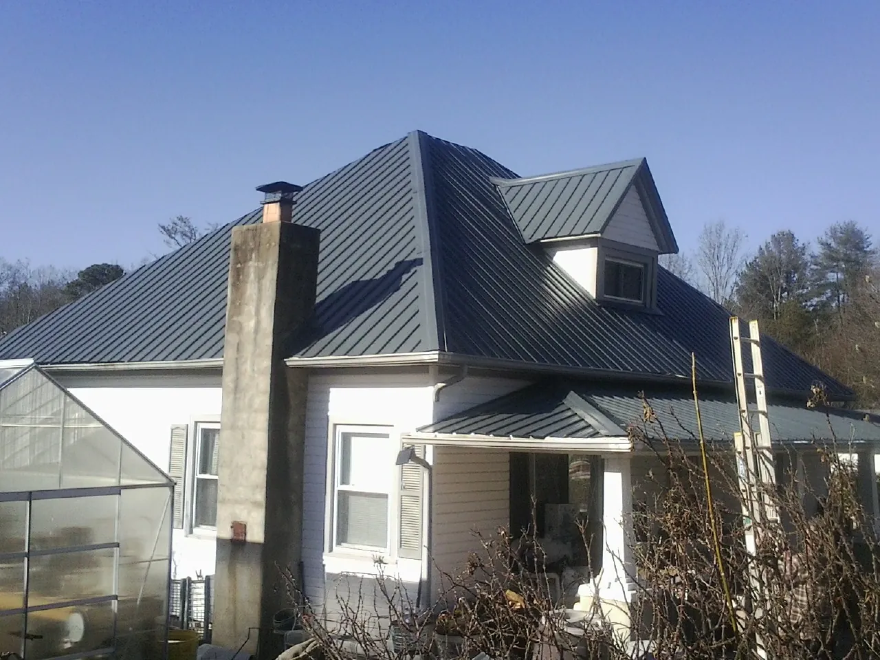 Dark blue standing seam metal roof on a white farmhouse with dormer — Slate & Tile Roof Repair by Roofing Brothers in Carefree