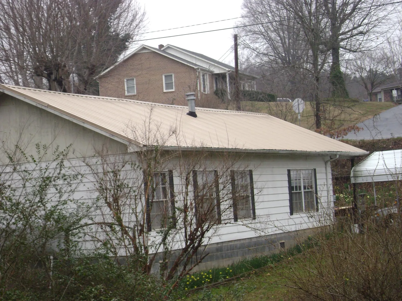 Tan metal roof on a white sided house set into a hillside — Commercial Roofing by Roofing Brothers in Carefree