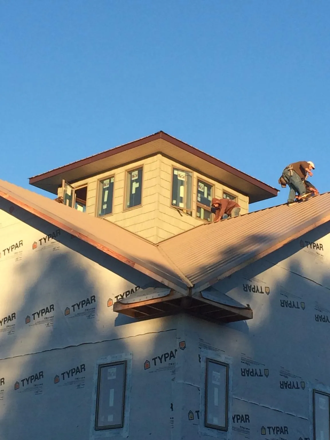 Roofers working around a rooftop cupola on a new metal roof at sunset — Roof Waterproofing in Carefree by Roofing Brothers